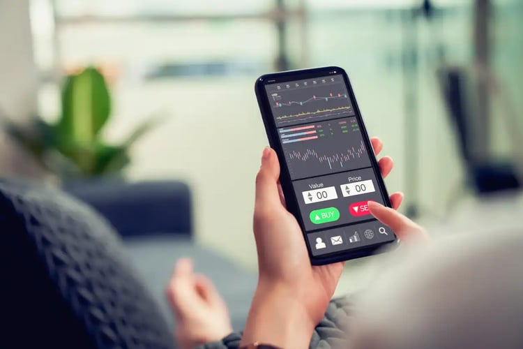 A rear view shot of  a Gen Zer using their phone to peruse the stock market.