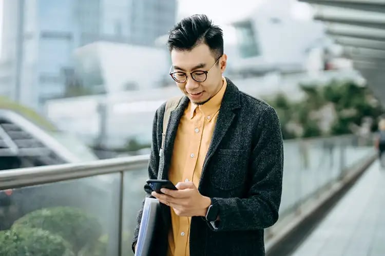 A wide shot of a businessman checking his phone after receiving texts from your bank.