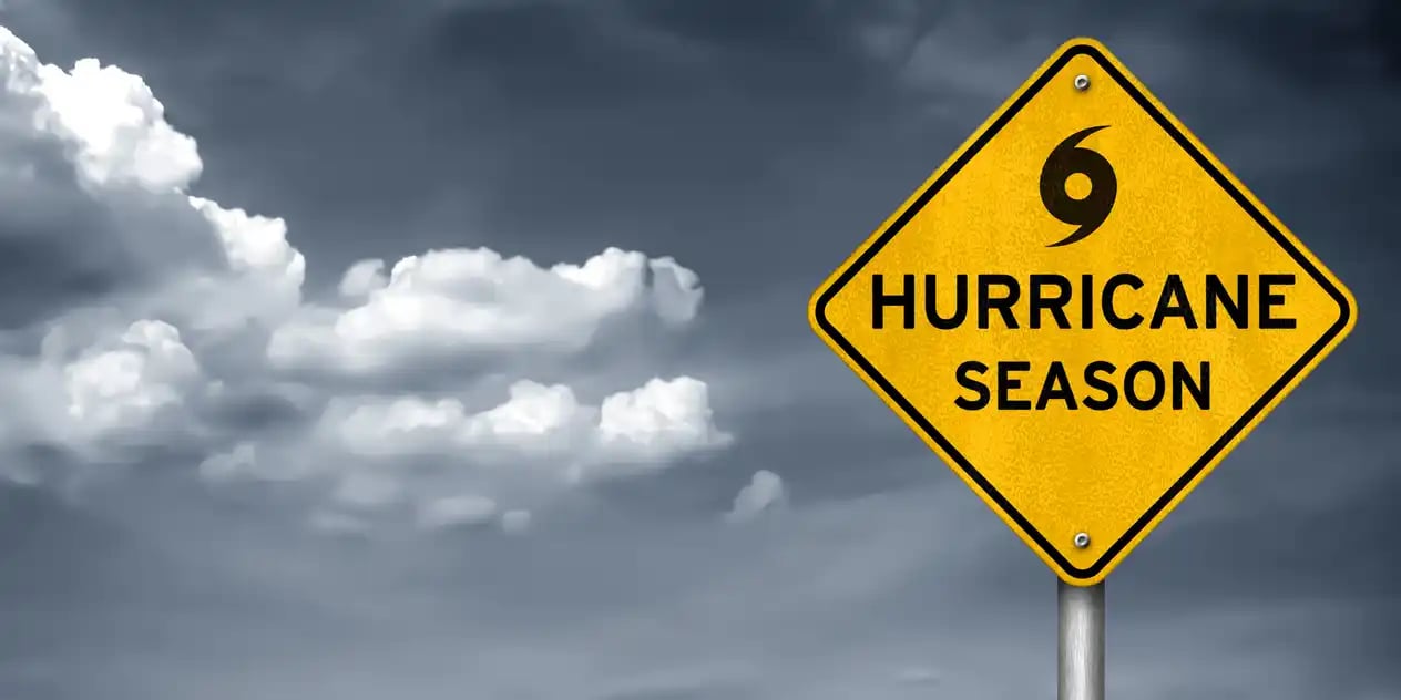 A yellow sign in front of a stormy backdrop indicating hurricane season in Houston.