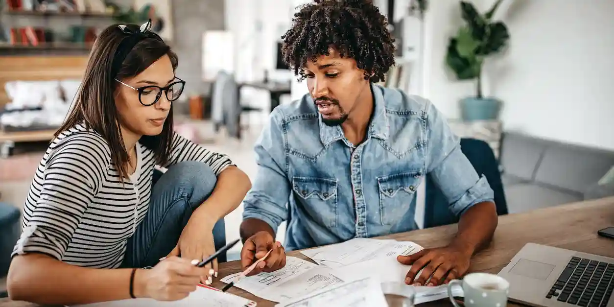 A couple bent over the paperwork for their finances, trying to budget better. A couple bent over the paperwork for their finances, trying to budget better.